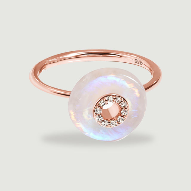 A rose gold ring with a polished slender band and an iridescent moonstone disc on a light gray background.