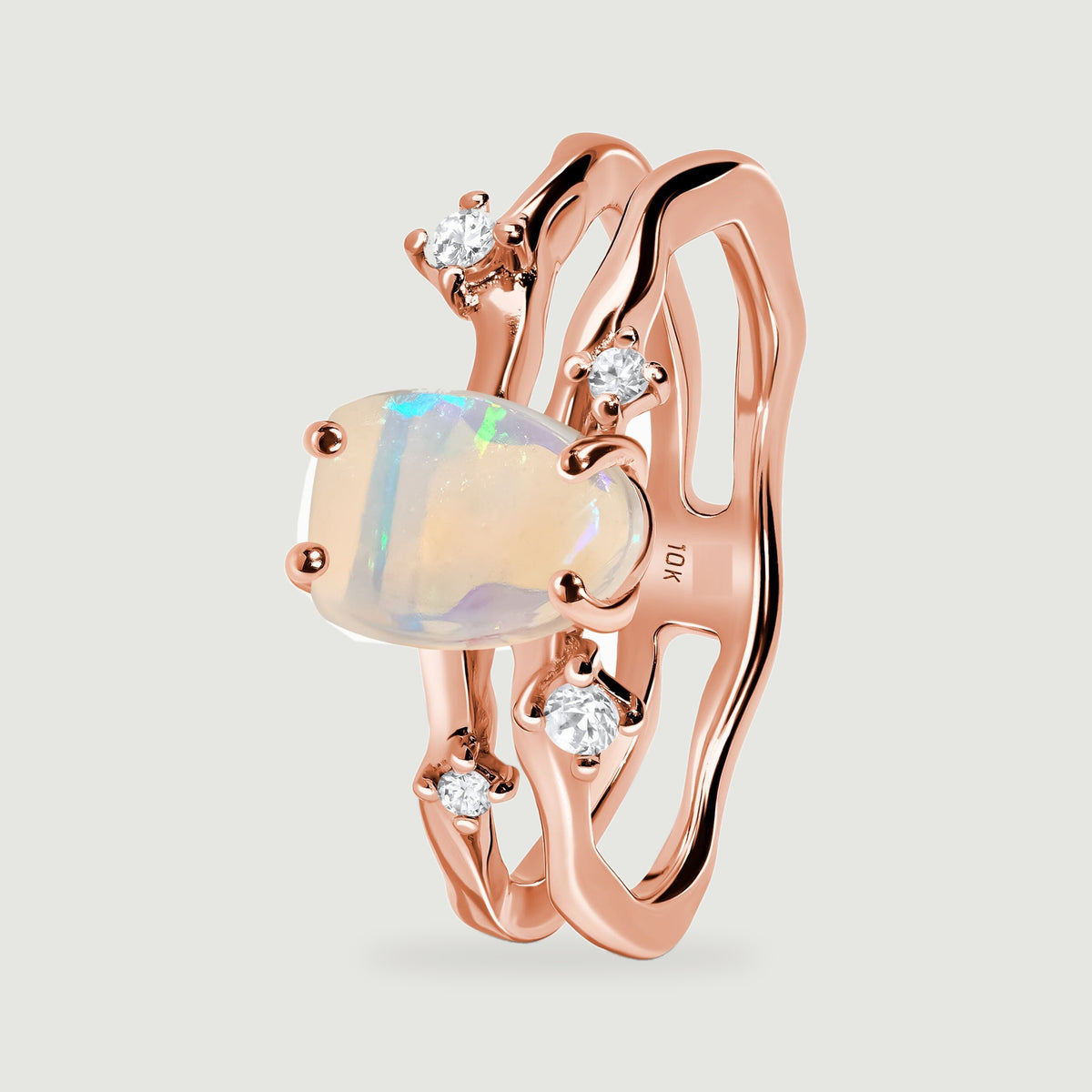 The upright rose gold ring shows its raised opal setting and open double band from an oblique angle.