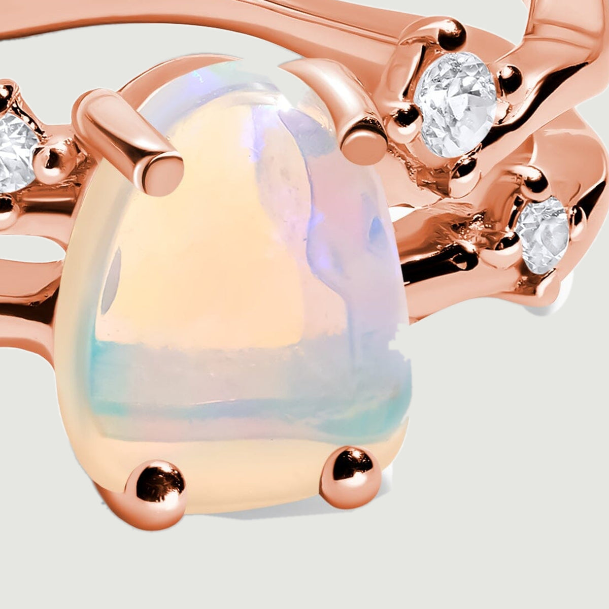 A close-up shows the milky opal held by rounded rose gold prongs beside clear accent stones.