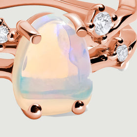 A close-up shows the milky opal held by rounded rose gold prongs beside clear accent stones.