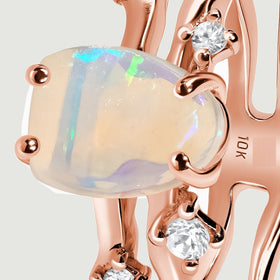 The opal displays green and blue reflections above the polished rose gold band in this side detail.