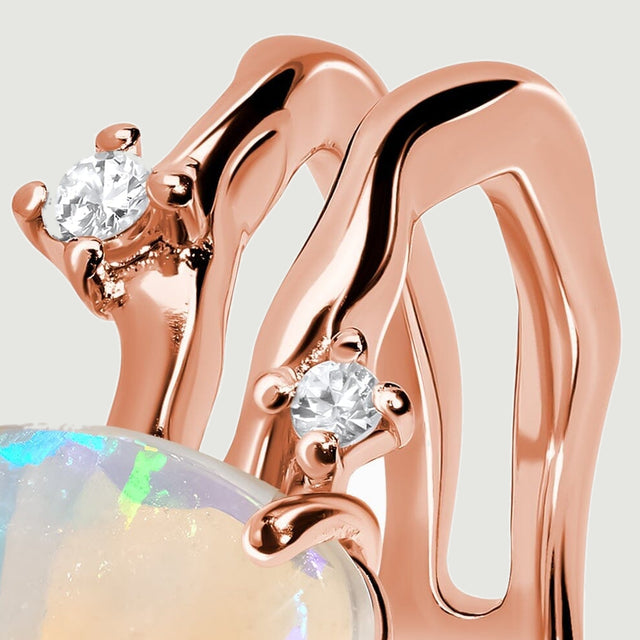 A close-up shows the undulating rose gold double band beside two round clear stones.