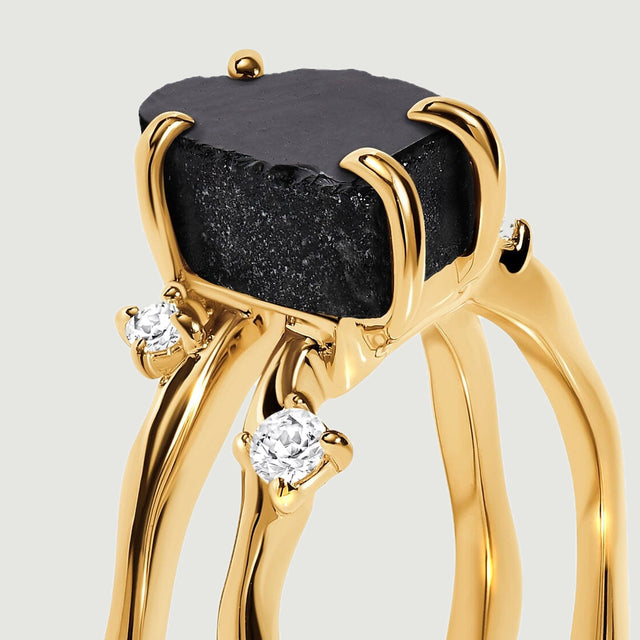 The raised black obsidian and round stone settings are shown close up above the yellow gold bands.