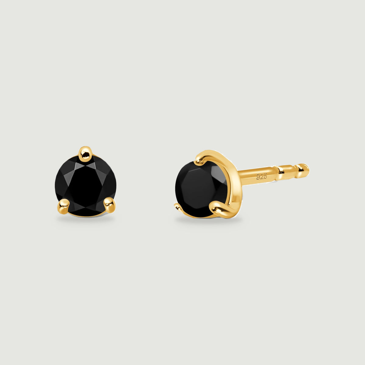 Round black obsidian earrings with yellow gold prongs are arranged to reveal their fronts and one post.