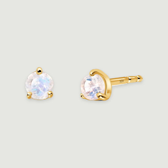 Two yellow gold moonstone earrings rest together, and a 10K stamp is visible on the exposed post.