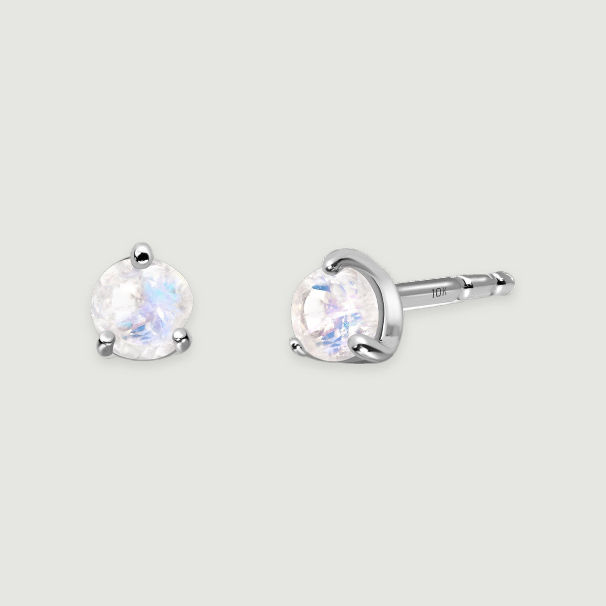 Round moonstone studs in white gold show iridescent stones and a 10K mark on one post.