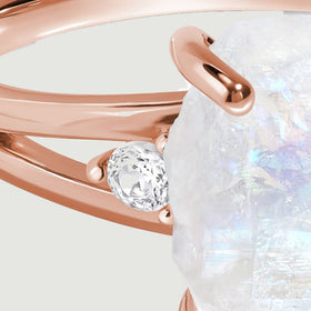A round clear side stone sits between the two polished rose gold arms of the split band.