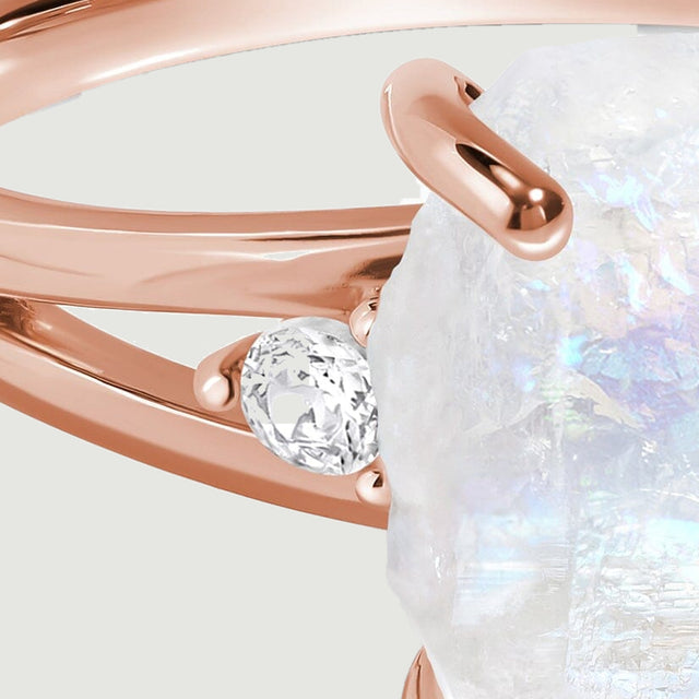A round clear side stone sits between the two polished rose gold arms of the split band.