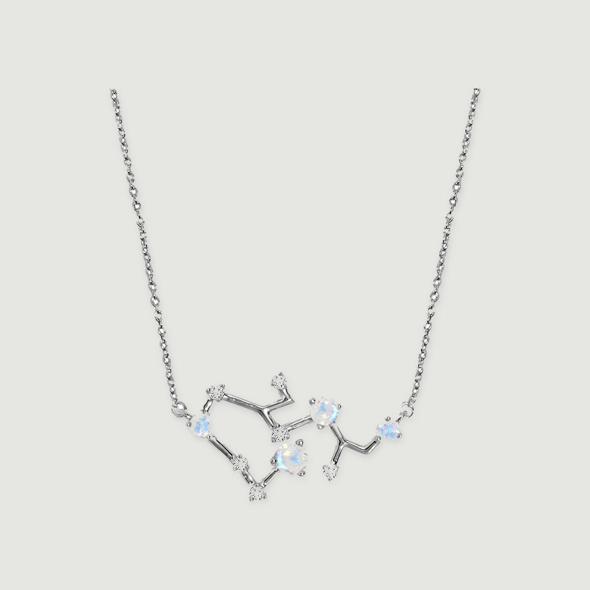 A silver necklace with a fine link chain and an open branching pendant rests against a light gray background.