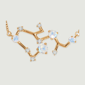 A close view shows yellow gold branches joining round iridescent stones and smaller clear stones.