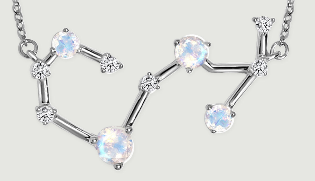 Silver bars connect four round iridescent stones and smaller clear stones across the open constellation pendant.
