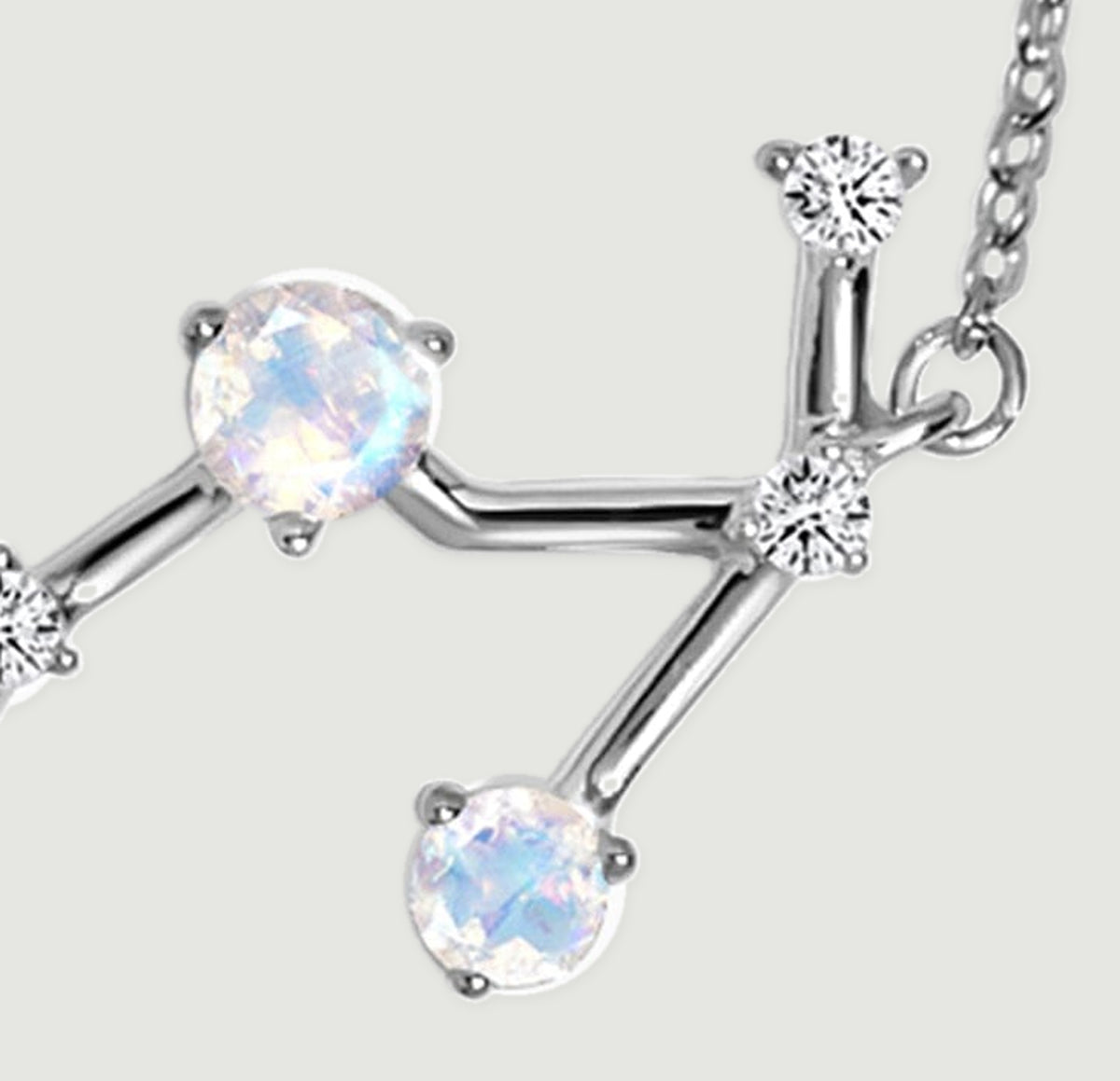 The right branch of the silver pendant has two pale round stones and clear accents beside the chain attachment.