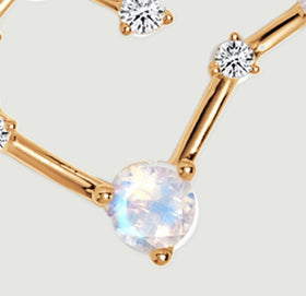 A large iridescent round stone sits in gold prongs between polished bars beneath a smaller clear stone.