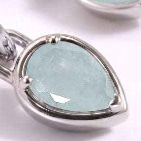 A close view shows a pale blue aquamarine pear held by three rounded silver-tone prongs.