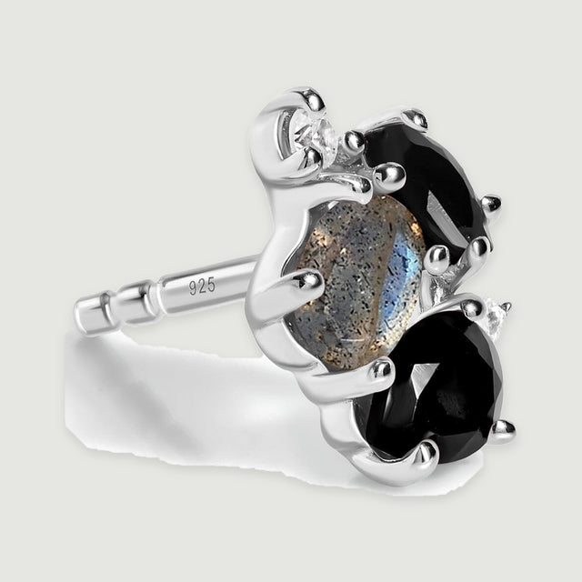 A sterling silver stud earring is shown at an angle with its straight post and the open sides of its gemstone settings visible.