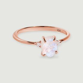 A rose gold ring with a softly iridescent raw moonstone is shown with its complete polished band.
