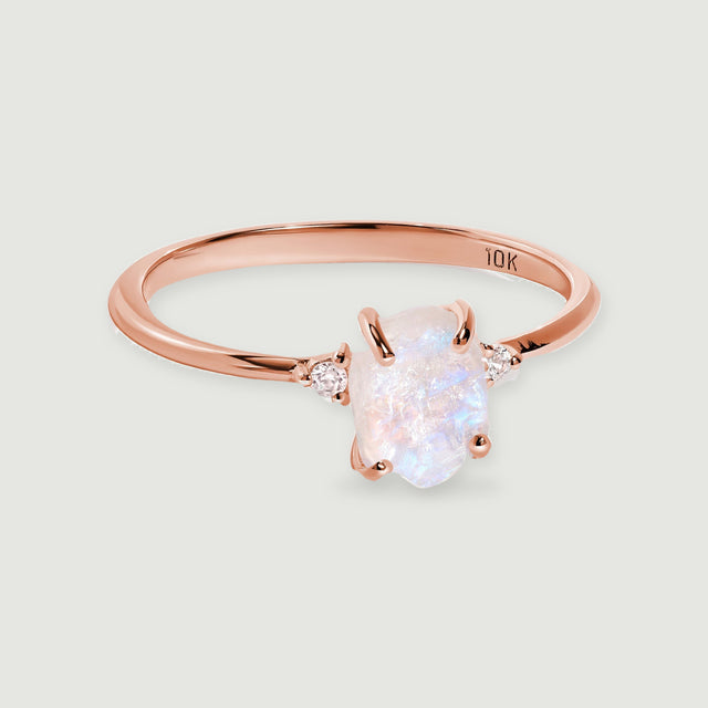 A rose gold ring with a softly iridescent raw moonstone is shown with its complete polished band.