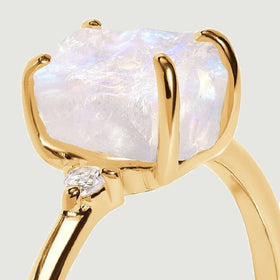 The yellow gold prongs hold a rough moonstone above a diamond accent in this close side view.