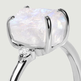 A close side view shows a raw moonstone, white gold claws and a round diamond beside the raised setting.