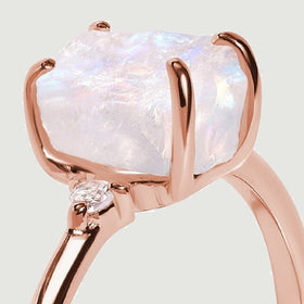 Rose gold claws wrap around the textured moonstone, with one round diamond visible at the shoulder.