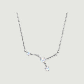 A sterling silver chain frames three pale round stones and two small clear accents on a light gray background.