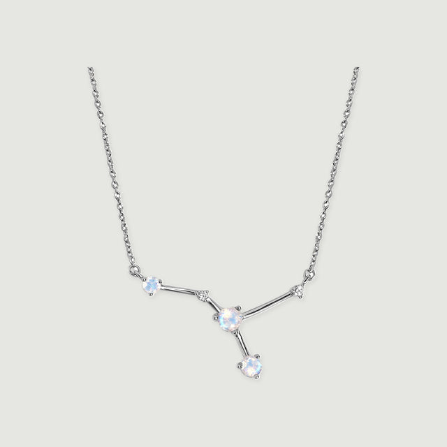 A sterling silver chain frames three pale round stones and two small clear accents on a light gray background.