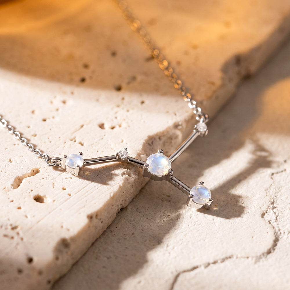 The silver necklace rests across pale stone steps with the raised prong settings visible in angled light.