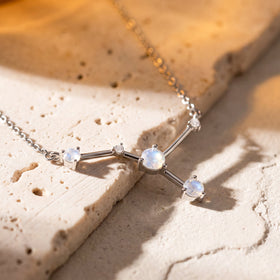 The silver necklace rests across pale stone steps with the raised prong settings visible in angled light.