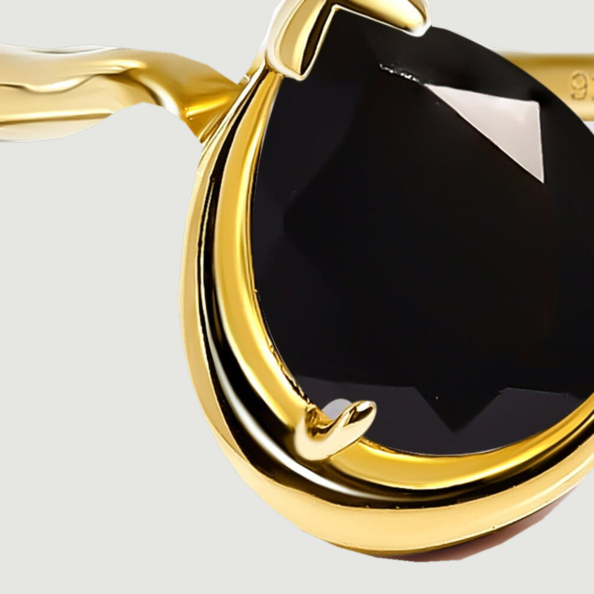 The curved left shoulder meets the raised gold rim beside the black stone.