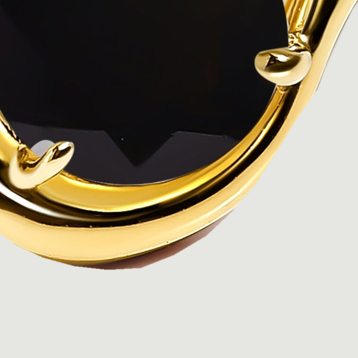 Two gold claws hold the rounded end of the black stone above a smooth curved rim.