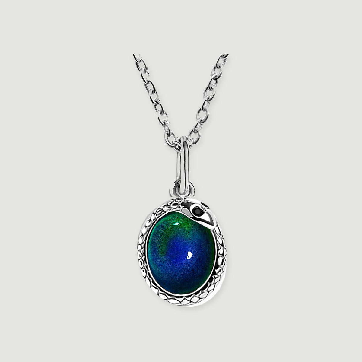 A silver-toned necklace with an oval blue-green pendant rests centrally on a light gray background.
