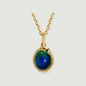 A yellow-gold-toned necklace displays a glossy oval stone and a textured rim against pale gray.