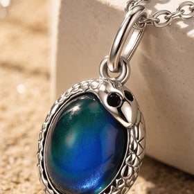 A close view shows a blue oval cabochon, black eye accents, and a silver-toned textured border beside pale stone.