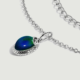 An angled silver-toned pendant reveals the raised blue-green cabochon and patterned side of its setting.