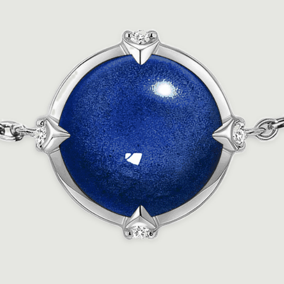 The round blue cabochon fills the frame beside silver tone prongs, clear accent stones, and fine chain links.