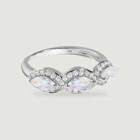 A white gold ring displays three iridescent marquise moonstones with curved diamond borders on a light gray surface.