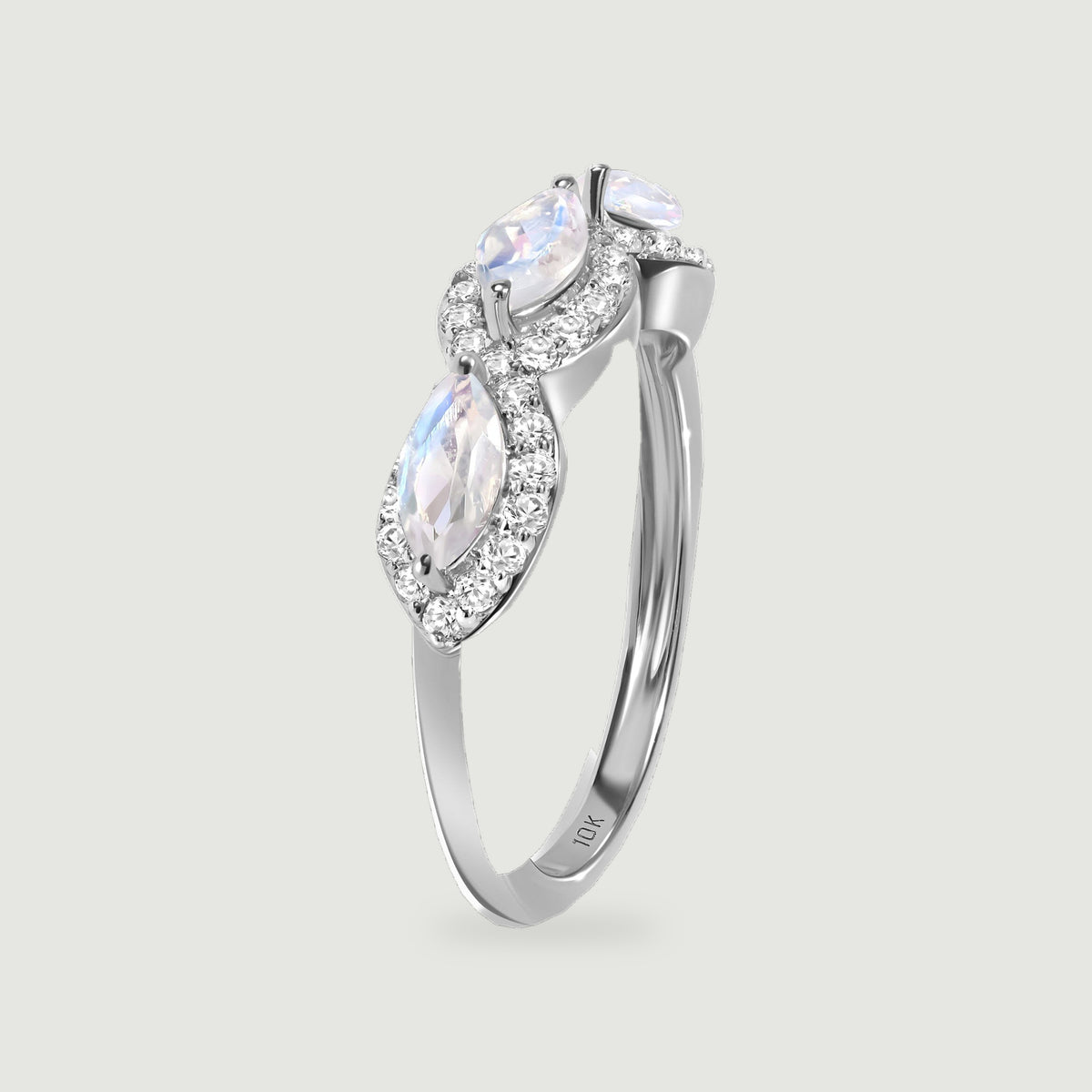 An upright white gold ring reveals the side of its moonstone settings and a slim polished band.