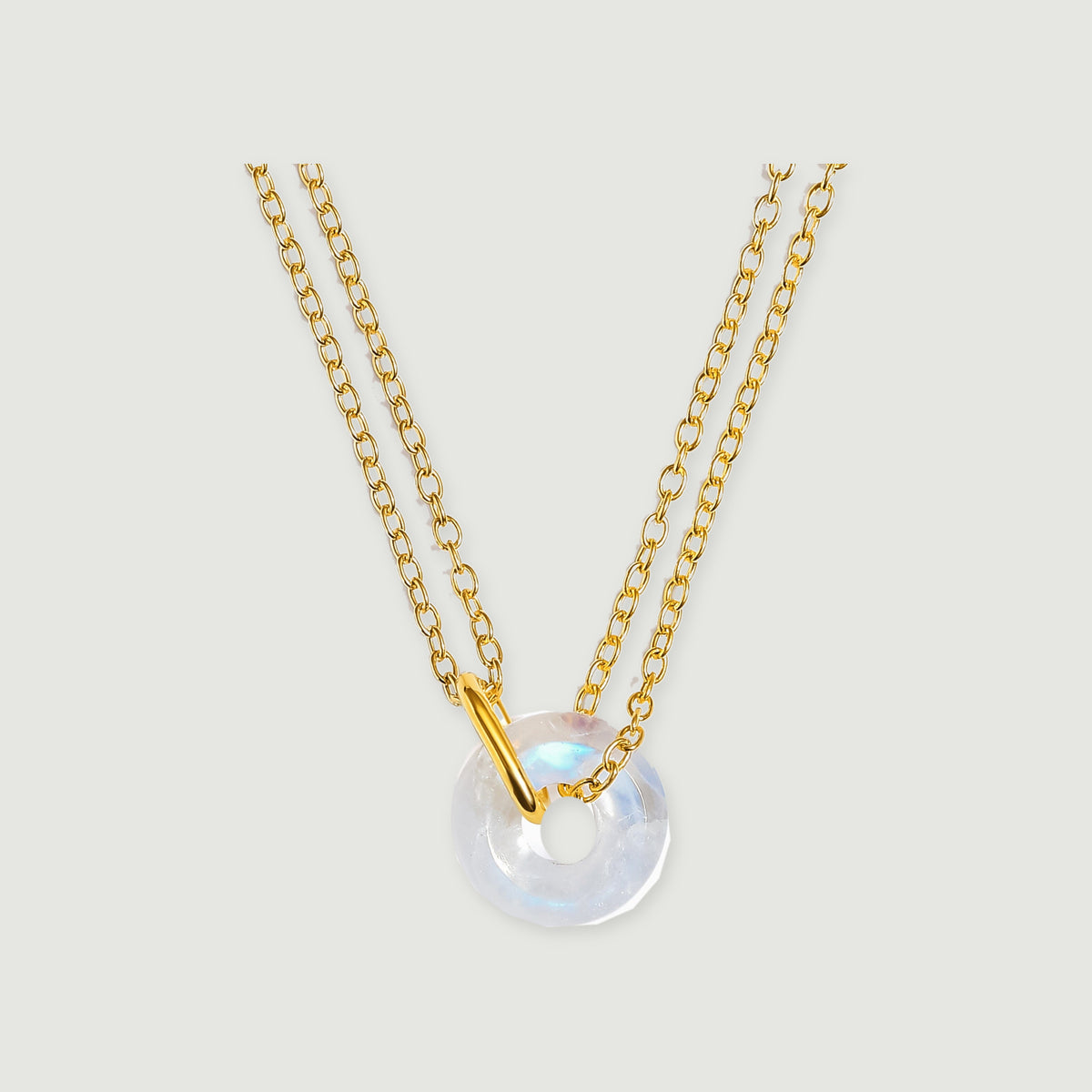 A yellow gold vermeil necklace with an open-centre moonstone pendant is shown against light grey.