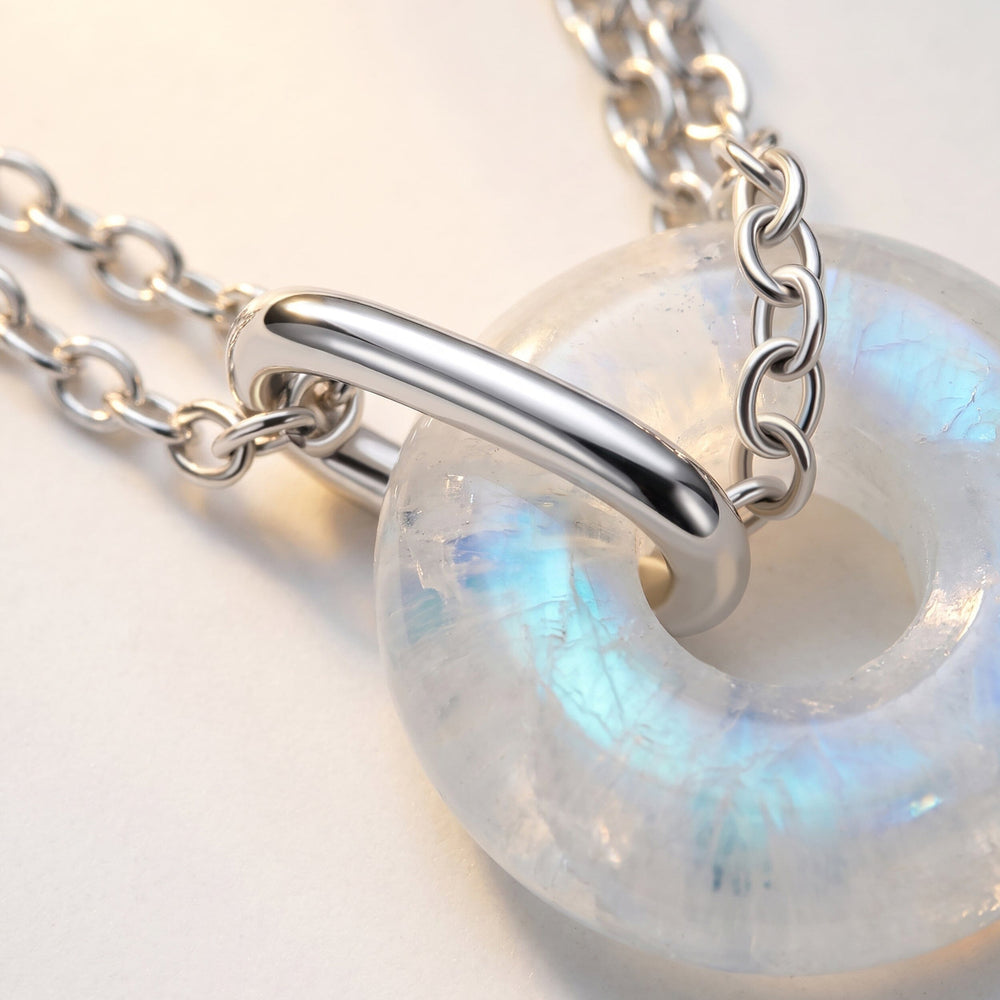 A close view shows blue reflections in the moonstone beside polished silver hardware and oval chain links.
