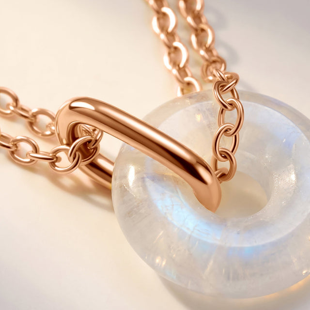 The rounded moonstone and rose gold vermeil connector fill a close view with a pale blue sheen in the stone.
