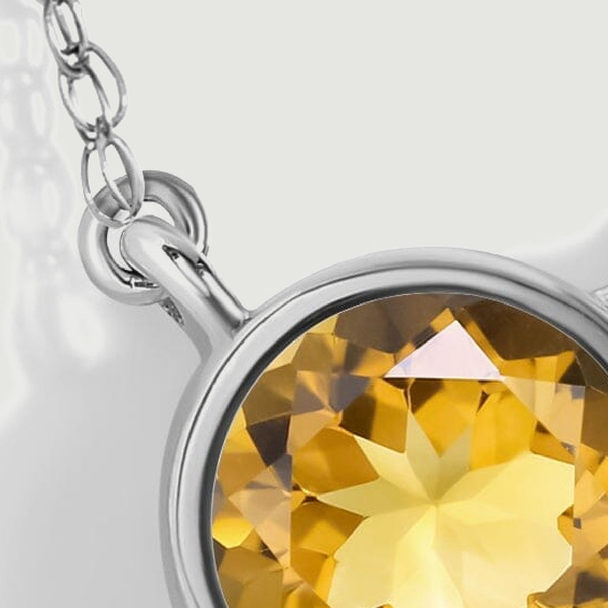 A close detail shows the left oval chain connection, its round joining loop, and the upper edge of the white gold citrine bezel.