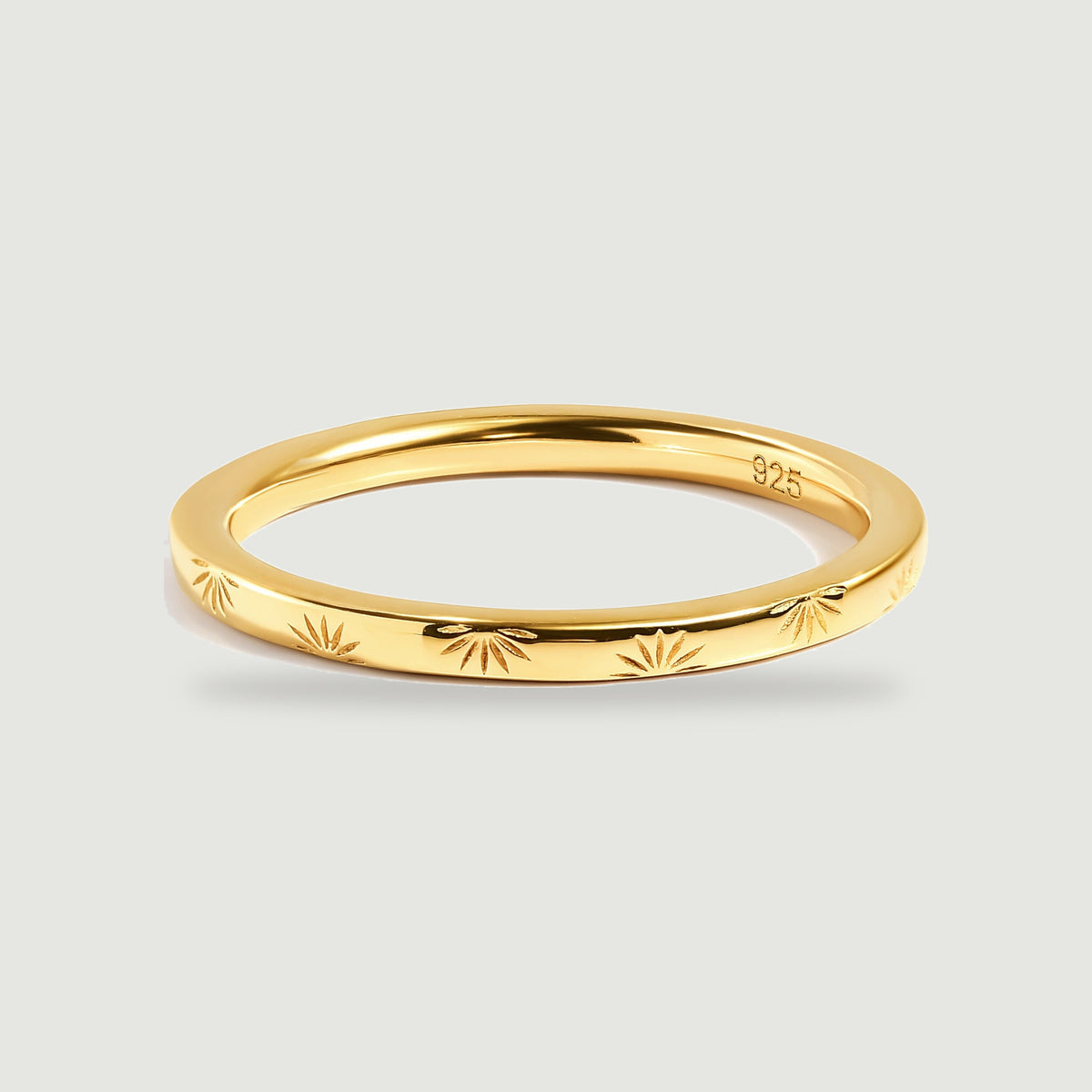 A yellow gold band displays alternating engraved rays and a smooth reflective interior.