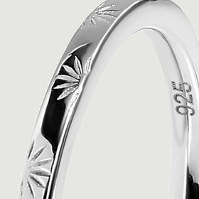 A close view shows the silver band curving around its engraved rays and inner 925 mark.
