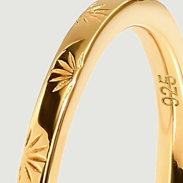 The upper arc of a yellow gold band reveals fine carved lines and rounded edges.