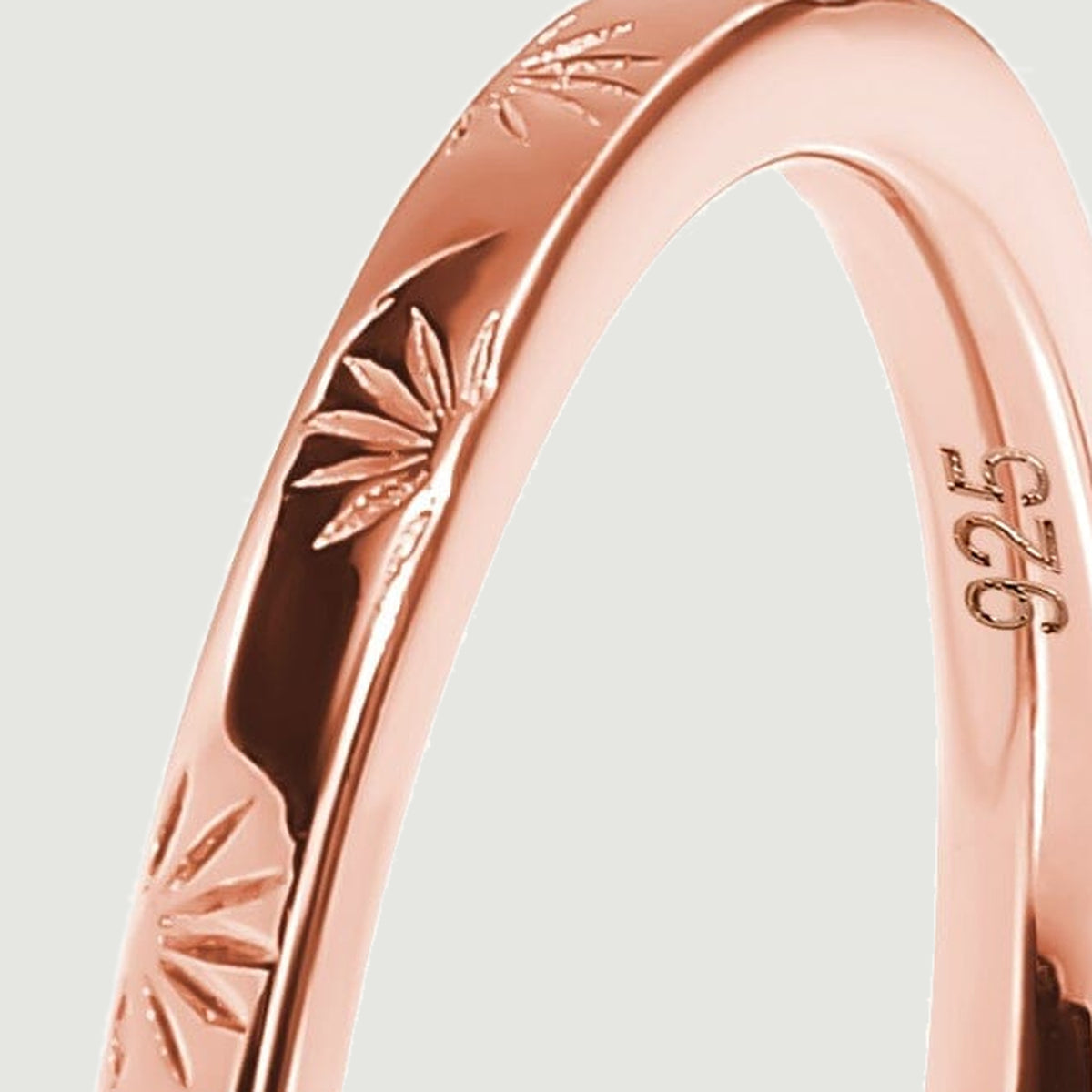 A rose gold ring curves through the frame with radiating engravings along its outer face.