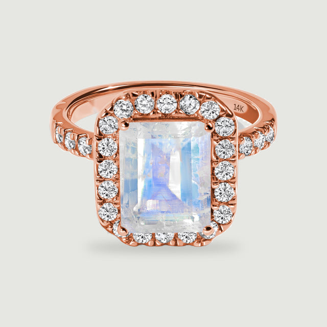 A rose gold ring has a rectangular iridescent moonstone surrounded by diamonds and a diamond-set band.