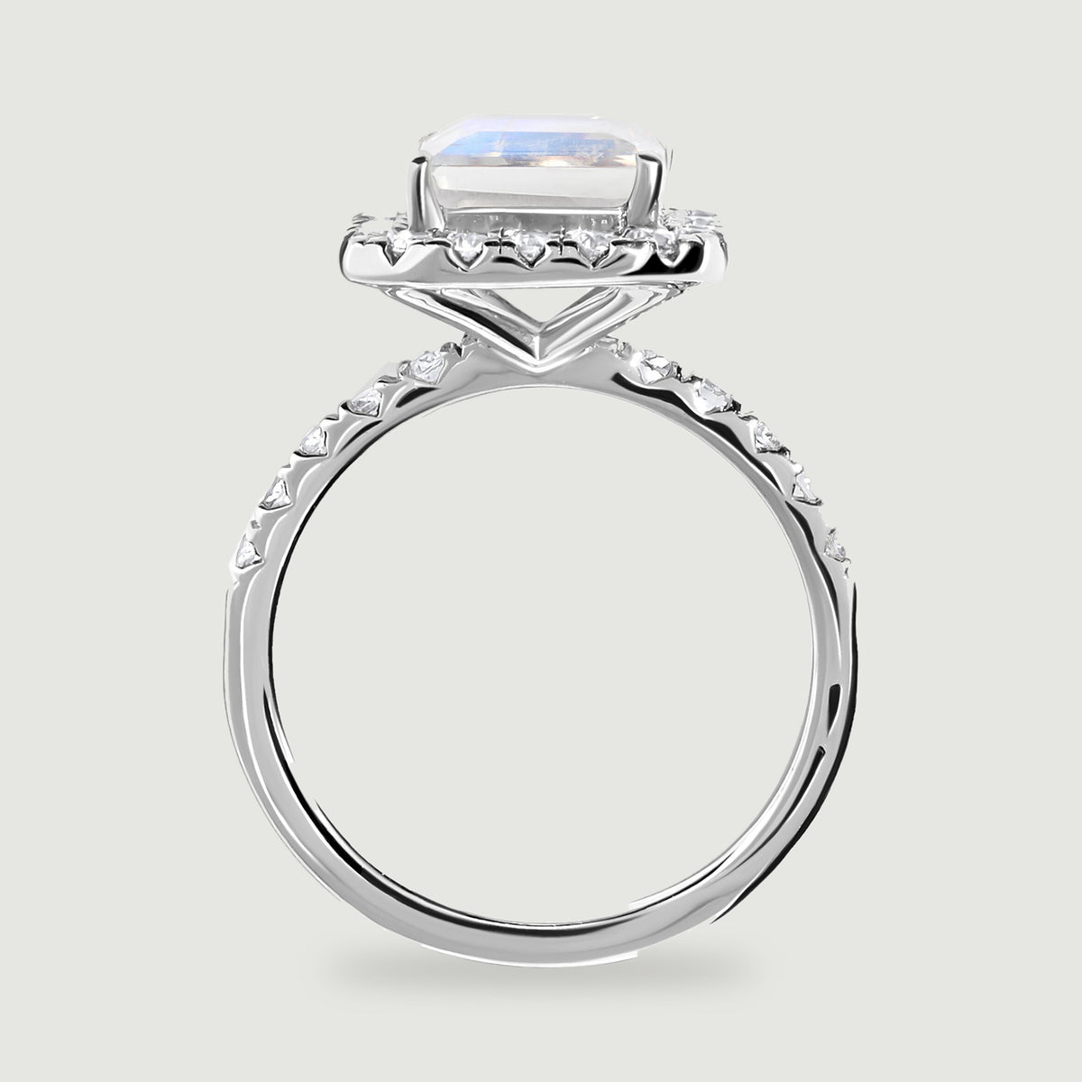 A white gold ring is viewed from the side with a raised rectangular stone and diamonds along the shoulders.