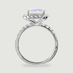 A white gold ring is viewed from the side with a raised rectangular stone and diamonds along the shoulders.