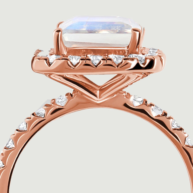 Rose gold supports form an open triangular gallery beneath the moonstone and its diamond border.
