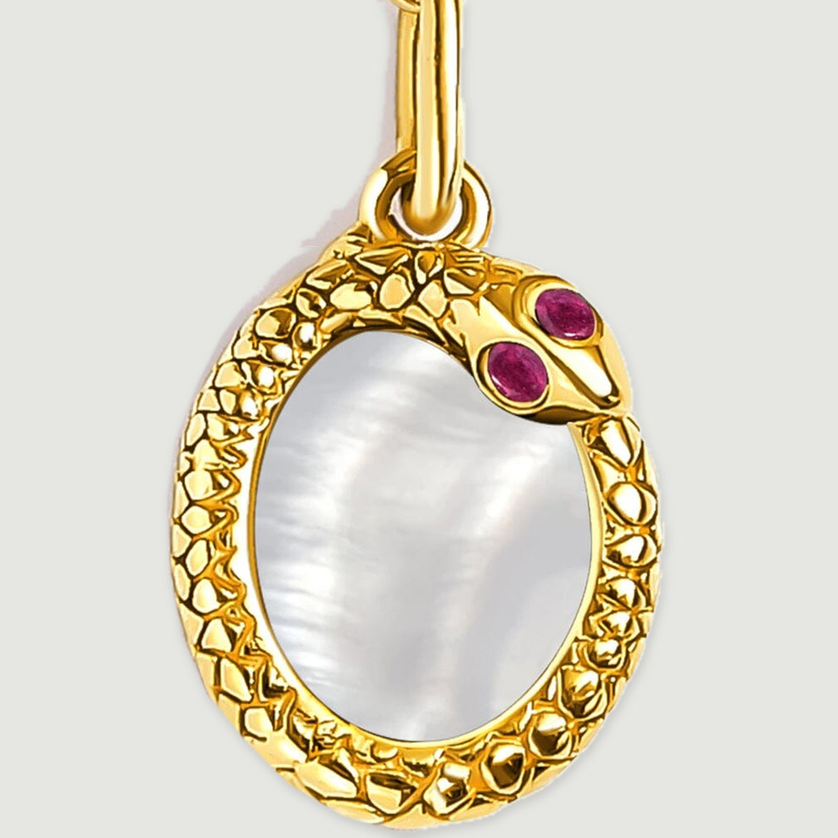 A close view shows the yellow gold plated rim around the oval mother of pearl and its two red details.